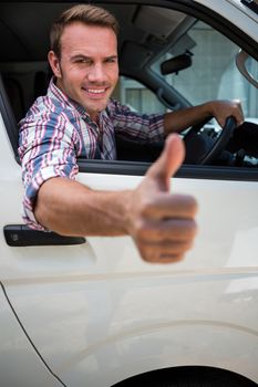 Portrait of young man showing thumbs up sign while driving the car