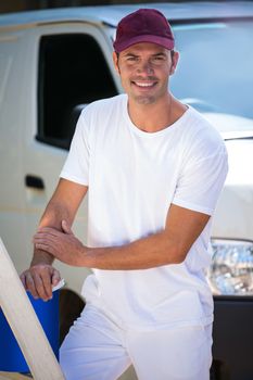 Portrait of painter with stepladder and bucket standing near his van