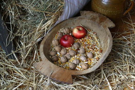 An apple and walnuts in an old wooden basket