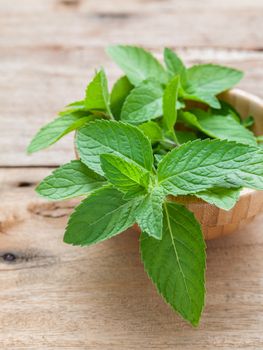 Closeup fresh peppermint  leaves in the wooden bowl on rustic table. Shallow dept of field .