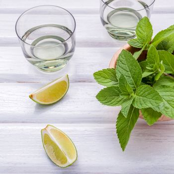 Ingredients for making mojitos mint leaves, lime,lemon and vodka on rustic background.