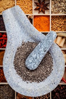 Assortment of spices food cooking ingredients in wooden box and mortar  set up on wooden table.