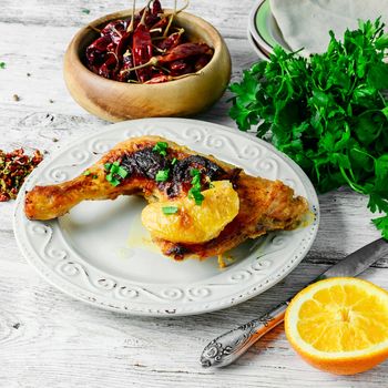 Plate of fried chicken thigh and fresh herbs.Light background