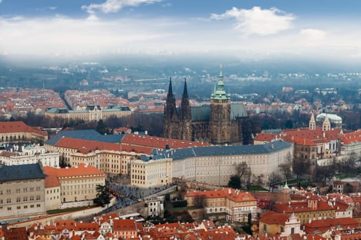 General top view of historical gothic Prague cityscape with old buildings and towers around, on cloudy sky background.