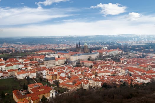 General top view of historical gothic Prague cityscape with old buildings and towers around, on cloudy sky background.