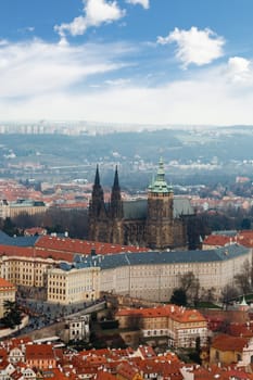 General top view of historical gothic Prague cityscape with old buildings and towers around, on cloudy sky background.