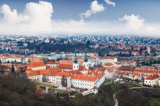 General top view of historical gothic Prague cityscape with old buildings and towers around, on cloudy sky background.