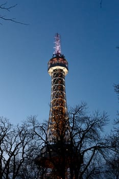 Bottom view of historical iron Petrin Tower, on bright blue sky background at sunset time.