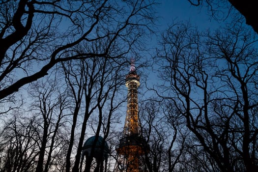 Bottom view of historical iron Petrin Tower, on bright blue sky background at sunset time.