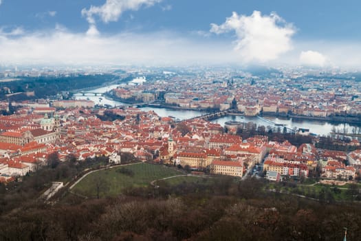 General top view of historical gothic Prague cityscape with old buildings and towers around, on cloudy sky background.