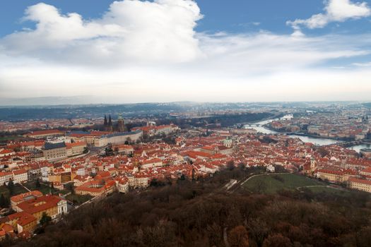 General top view of historical gothic Prague cityscape with old buildings and towers around, on cloudy sky background.