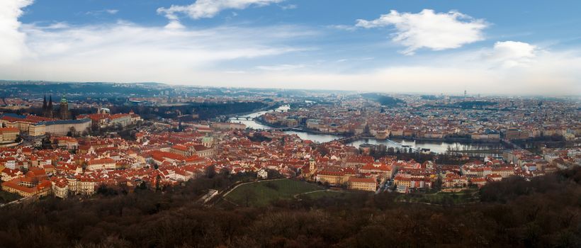 General top view of historical gothic Prague cityscape with old buildings and towers around, on cloudy sky background.