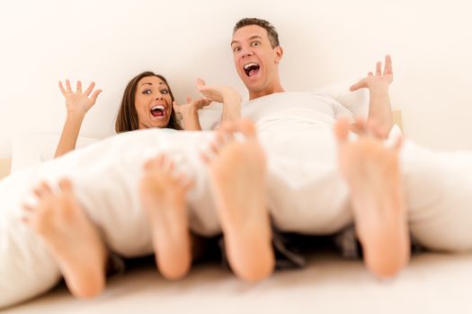 Beautiful young smiling couple having fun in bed in the morning. 