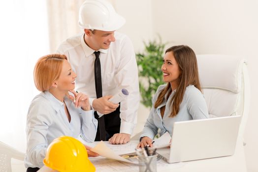 Smiling architect discussing and looking the architectural plans in office.