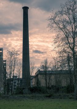 In the picture a large chimney located close to homes, split toning color used.