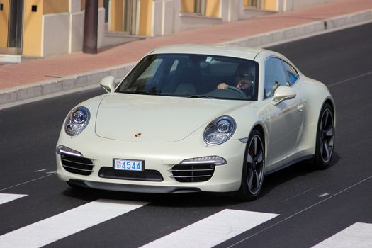 Monte-Carlo, Monaco - April 6, 2016: Porsche 911 Carrera S on Avenue d'Ostende in Monaco. Man Driving an Expensive White Porsche 911 50th anniversary edition in the south of France 