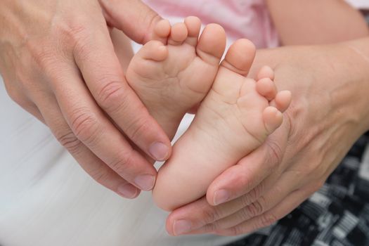 Cute baby feet in her mothers' hands