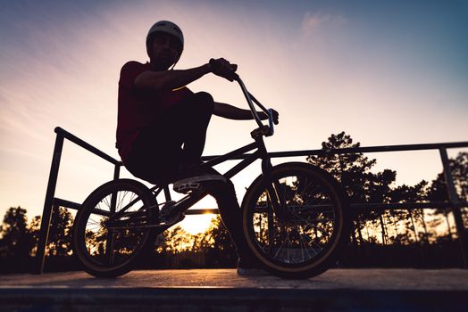 Bmx rider and his bike silhouette against sky at sunset.