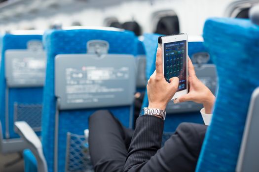 Businessman using his tablet phone on airplane. Business travel and communication concept. 