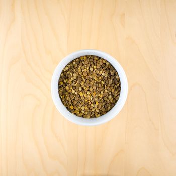 Pile of raw dry brown lentils in cup, top view, square composition, food preparation, copy space