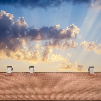 cloudy blue sky with sun flares, tiled roof top background