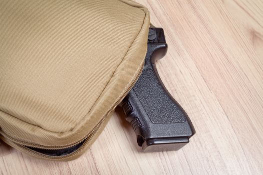 weapon gun in bag, khaki or sand color, on table background