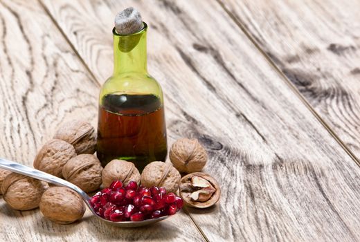 Tincture or juice of Pomegranate and ripe red seeds in an iron spoon on old wooden textured table