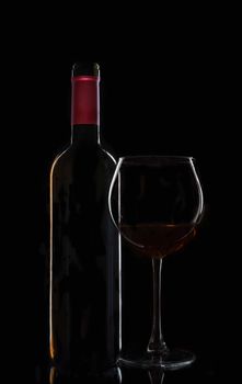 bottle of wine with a glass on a black background