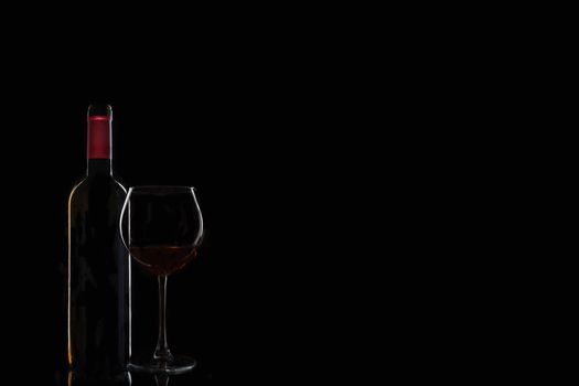 bottle of wine with a glass on a black background