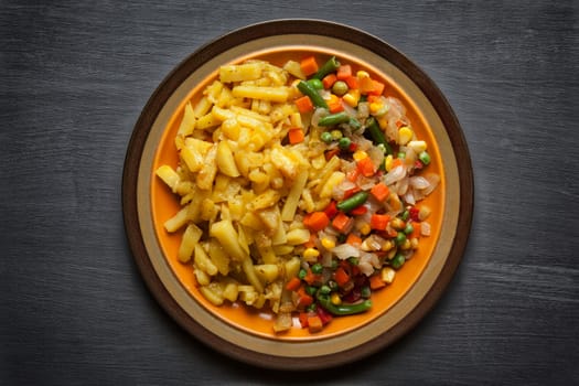 vegetables and potatoes close up on a plate on the table. horizontal