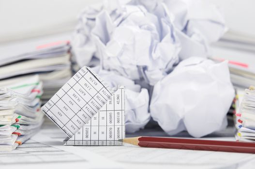 Close up bankruptcy of house with pencil on finance account have blur stack of paper ball between pile of paperwork as background.