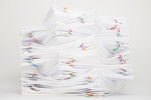 Overload document of receipt and report with colorful paperclip on white table.