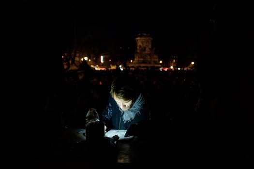 FRANCE, Paris: A man reads as thousand militants of the Nuit debout (Standing night) movement gather on April 7, 2016 at the Place de la Republique in Paris, as participants plan to spend the night camped out to protest against the government's planned labour reform and against forced evictions. It has been one week that hundred of people have occupied the square to show, at first, their opposition to the labour reforms in the wake of the nationwide demonstration which took place on March 31, 2016.