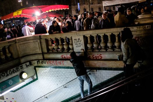 FRANCE, Paris: A man writes on a subway wall No justice, no peace as thousand militants of the Nuit debout (Standing night) movement gather on April 7, 2016 at the Place de la Republique in Paris, as participants plan to spend the night camped out to protest against the government's planned labour reform and against forced evictions. It has been one week that hundred of people have occupied the square to show, at first, their opposition to the labour reforms in the wake of the nationwide demonstration which took place on March 31, 2016.