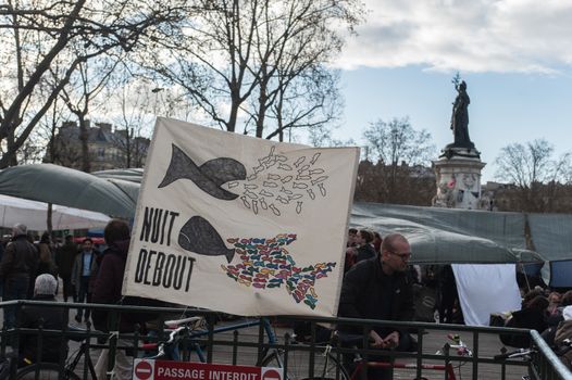 FRANCE, Paris: A picture is taken of a sign reading Nuit Debout (Standing Night) as thousand militants of the Nuit debout (Standing night) movement gather on April 7, 2016 at the Place de la Republique in Paris, as participants plan to spend the night camped out to protest against the government's planned labour reform and against forced evictions. It has been one week that hundred of people have occupied the square to show, at first, their opposition to the labour reforms in the wake of the nationwide demonstration which took place on March 31, 2016.