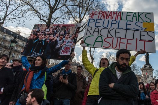 FRANCE, Paris: A protester holds a sign reading #PanamaLeaks, people, extortion is enough as thousand militants of the Nuit debout (Standing night) movement gather on April 7, 2016 at the Place de la Republique in Paris, as participants plan to spend the night camped out to protest against the government's planned labour reform and against forced evictions. It has been one week that hundred of people have occupied the square to show, at first, their opposition to the labour reforms in the wake of the nationwide demonstration which took place on March 31, 2016.