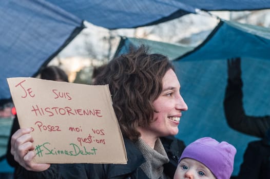 FRANCE, Paris: A woman holds a sign reading I am a historian, ask me your questions #StandingSciences as thousand militants of the Nuit debout (Standing night) movement gather on April 7, 2016 at the Place de la Republique in Paris, as participants plan to spend the night camped out to protest against the government's planned labour reform and against forced evictions. It has been one week that hundred of people have occupied the square to show, at first, their opposition to the labour reforms in the wake of the nationwide demonstration which took place on March 31, 2016.