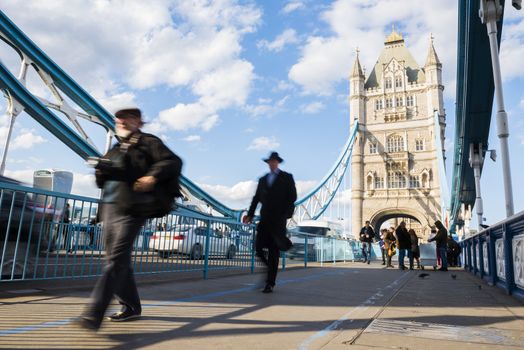 LONDON, UK – APRIL 05 2016: Motion blurred commuters crossing Tower Bridge during rush hour. Tower Bridge links the South of River Thames to the City area.
