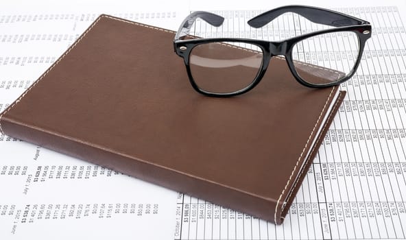 Notebook with glasses on paper bill background, business concept