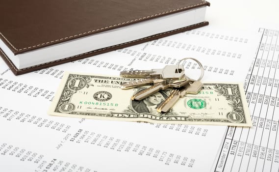 Notebook with keys and dollar on paper bill background, business concept