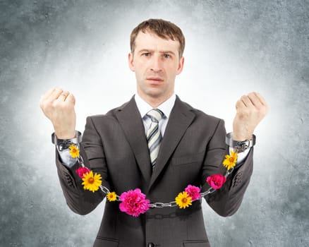 Businessman in cuffs with flowers on grey wall background