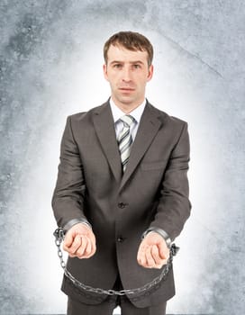 Angry businessman in cuffs on grey wall background