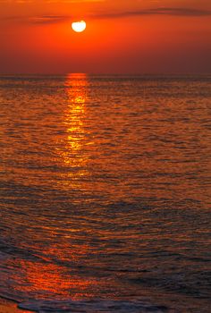 red sunset over the water. the rays of the setting sun reflected on the water surface