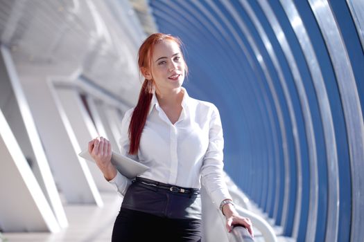 Beautiful modern businesswoman holding tablet computer inside modern building