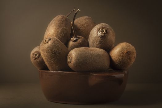 Kiwi in a bowl of brown on brown background to understand a principle of healthy eating