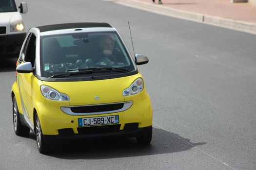 Monte-Carlo, Monaco - April 6, 2016: Yellow Compact Car Smart Fortwo on Avenue d'Ostende in Monaco. Man Driving a Yellow Car Smart Fortwo in the South of France