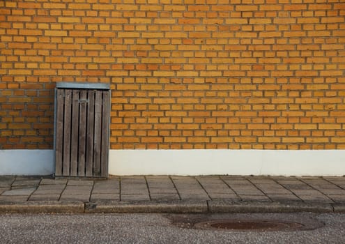 Wooden Outdoor Garbage Can with Yellow Brick Wall Background