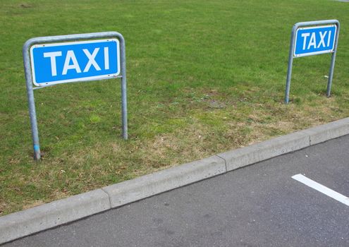Taxi Signs at Empty Parking Place in Perspective with Lawn in Background