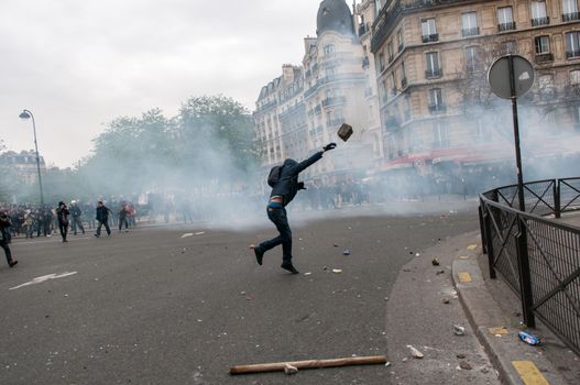 FRANCE, Paris: A protester throws an unidentifiable item to police forces during a demonstration against labour reform in Paris on April 9, 2016.