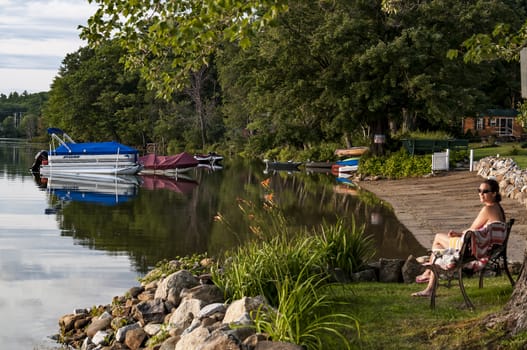 CHRYSTAL LAKE MAINE - JULY 30: young women enjoys her time on the lake shore on July 30, 2014 on Chrystal Lake in Maine